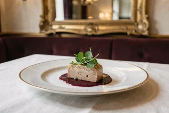 Assiette gastronomique raffinée servie dans un restaurant chic de la Rue de Rivoli à Paris, avec nappe en lin et vaisselle dorée