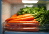 Carottes lavées dans un conteneur dans le frigo lumineux