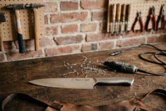 Couteau de cuisine gravé posé sur un établi en bois dans un atelier artisanal français