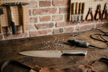 Couteau de cuisine gravé posé sur un établi en bois dans un atelier artisanal français
