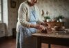Les traditions culinaires françaises qui perdurent pendant les fêtes Femme âgée préparant une bûche de Noël dans la cuisine